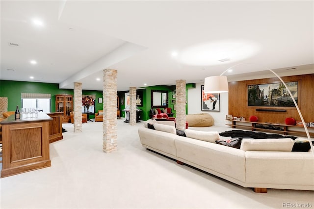 living room featuring light carpet, wood walls, and ornate columns