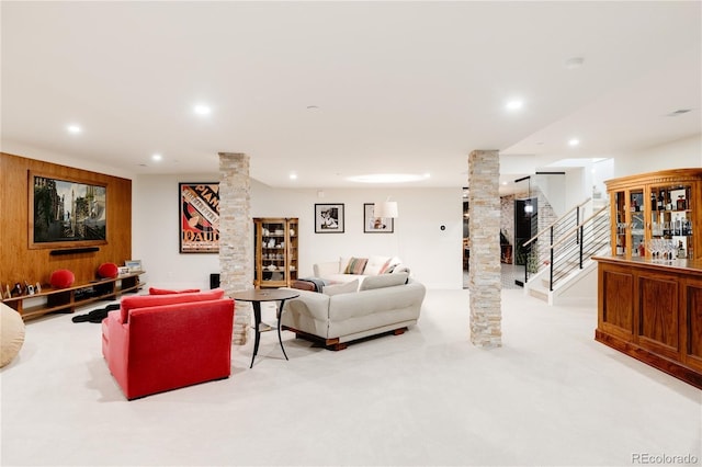 carpeted living room with wooden walls and ornate columns