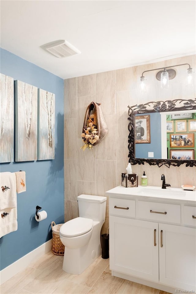 bathroom with vanity, toilet, and tile walls