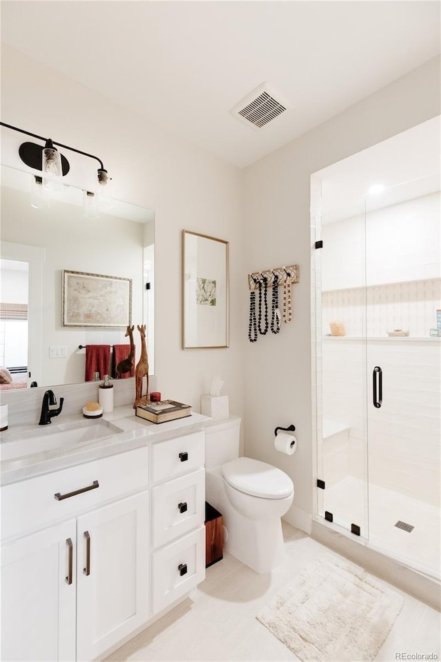 bathroom featuring a shower with door, toilet, vanity, and tile patterned flooring