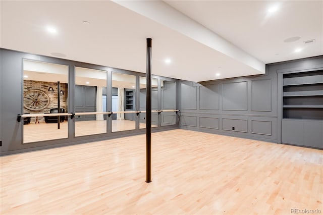 basement with built in shelves and light hardwood / wood-style flooring