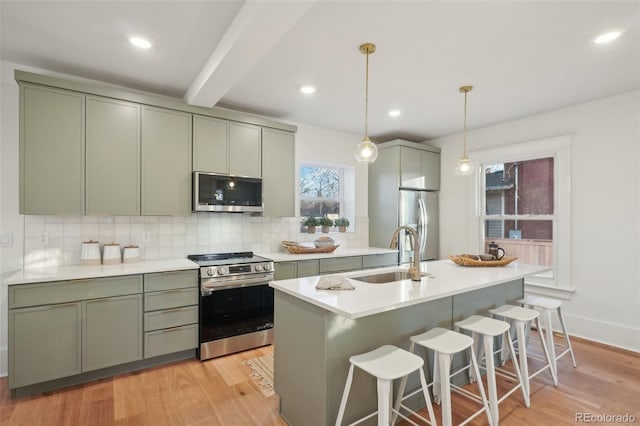 kitchen with appliances with stainless steel finishes, light hardwood / wood-style floors, beamed ceiling, sink, and decorative light fixtures