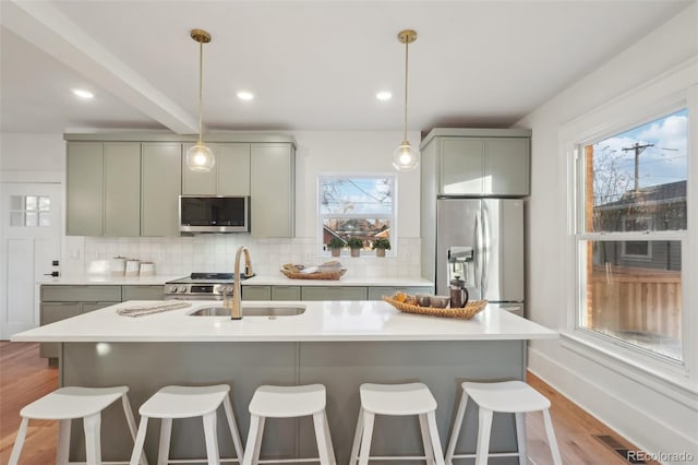 kitchen featuring a wealth of natural light, light hardwood / wood-style floors, decorative backsplash, appliances with stainless steel finishes, and sink