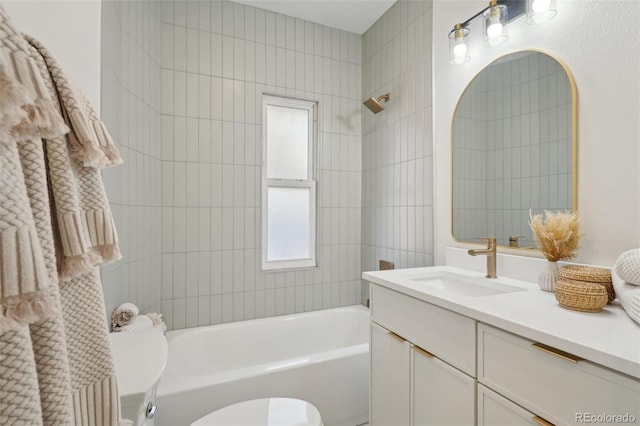 full bathroom with tiled shower / bath, vanity, and toilet