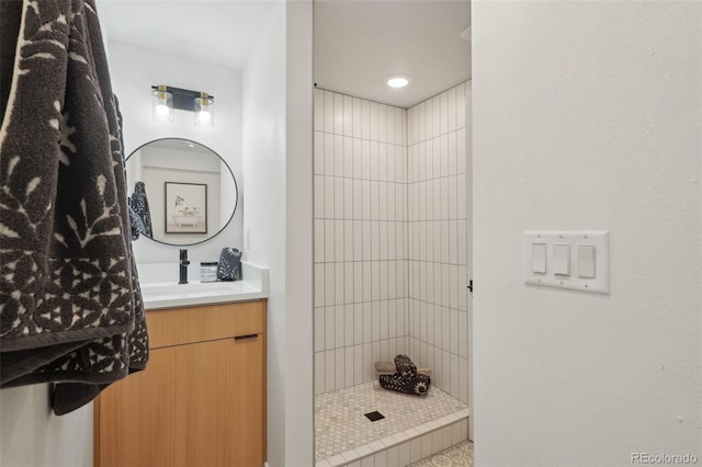 bathroom with a tile shower and vanity