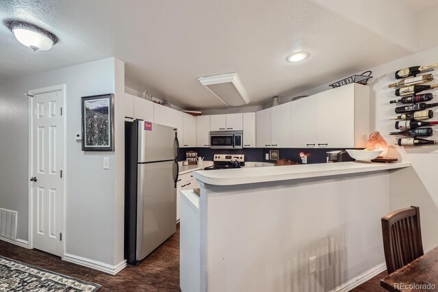 8767 E Dry Creek Rd Unit 1312, Englewood, CO 80112 - kitchen featuring appliances with stainless steel finishes, a peninsula, light countertops, white cabinets, and dark wood-style floors