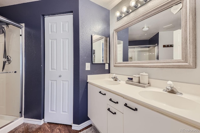 8767 E Dry Creek Rd Unit 1312, Englewood, CO 80112 - full bathroom with a textured wall, a stall shower, wood finished floors, baseboards, and double vanity