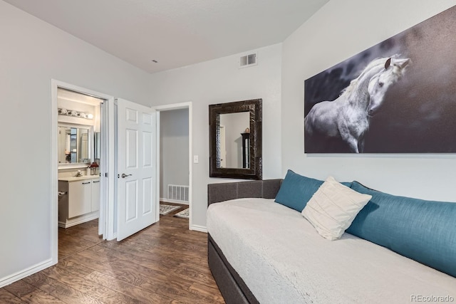 bedroom with dark wood-type flooring and connected bathroom