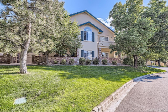 view of front of house featuring a balcony and a front lawn