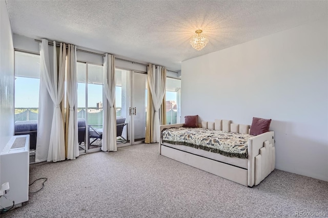 bedroom with a textured ceiling, an inviting chandelier, and carpet floors