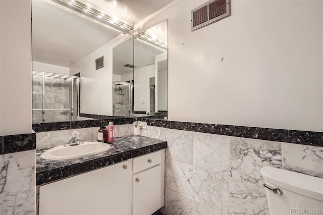 bathroom featuring tile walls, walk in shower, vanity, and toilet