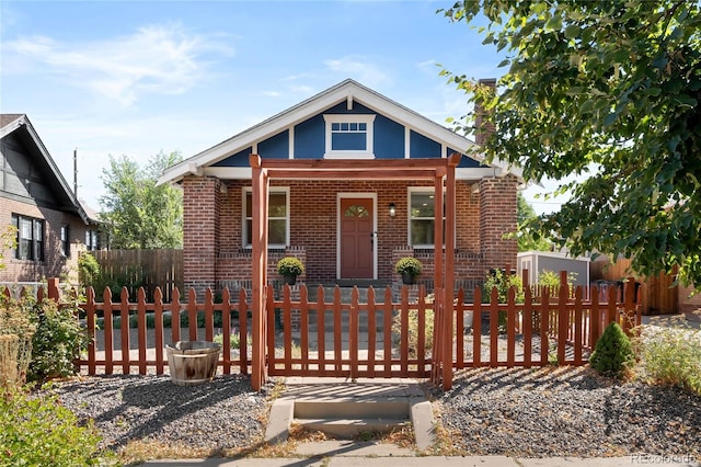 view of front facade featuring brick siding, a porch, and a fenced front yard