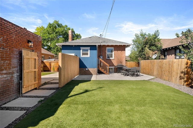 back of property with a chimney, fence, entry steps, a lawn, and a patio