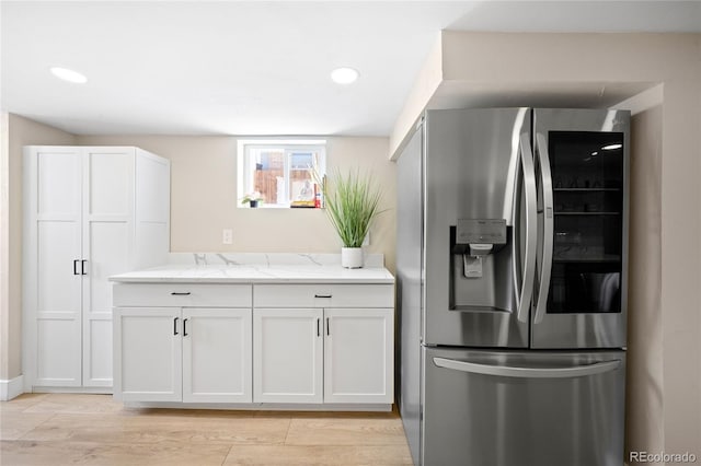 kitchen with recessed lighting, white cabinets, stainless steel fridge with ice dispenser, light wood-type flooring, and light stone countertops