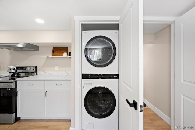 washroom featuring stacked washer and clothes dryer, recessed lighting, laundry area, light wood-style floors, and baseboards