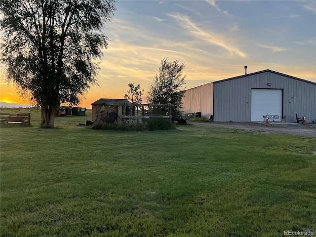 yard at dusk with a garage and an outdoor structure