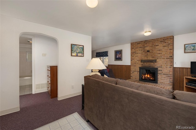 182 Colorado Dr, Tabernash, CO 80446 - living room with arched walkways, a fireplace, light carpet, wainscoting, and wood walls