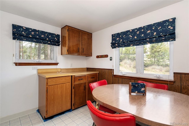 182 Colorado Dr, Tabernash, CO 80446 - kitchen with wainscoting, brown cabinetry, plenty of natural light, wood walls, and light countertops