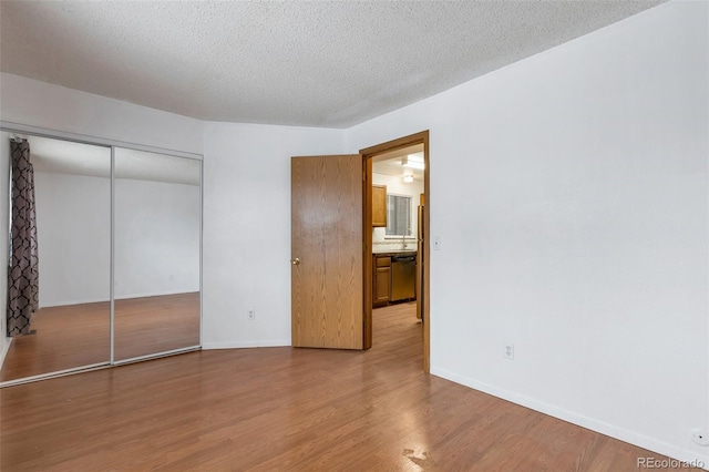 unfurnished bedroom featuring hardwood / wood-style floors, a textured ceiling, and a closet