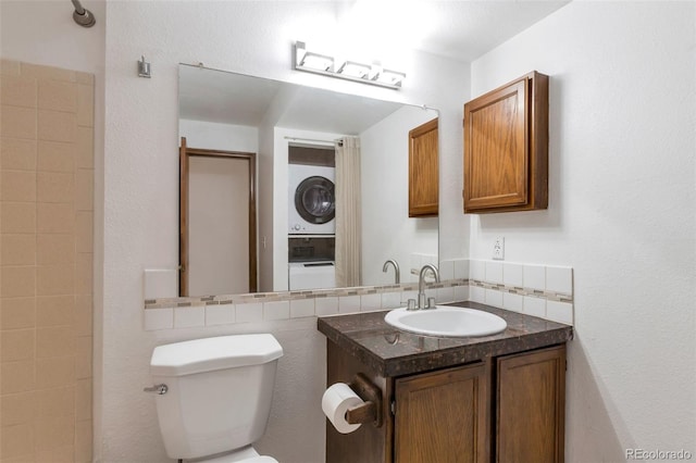 bathroom with stacked washer and dryer, vanity, toilet, and backsplash