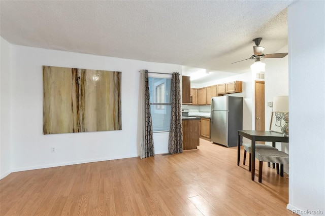 kitchen featuring ceiling fan, stainless steel fridge, a textured ceiling, and light hardwood / wood-style flooring