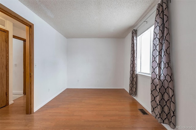 unfurnished room with a textured ceiling and light hardwood / wood-style flooring