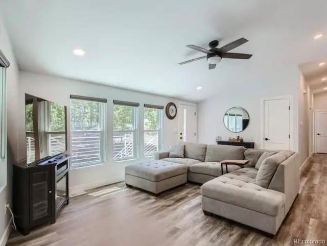 living area featuring lofted ceiling, wood finished floors, baseboards, and ceiling fan