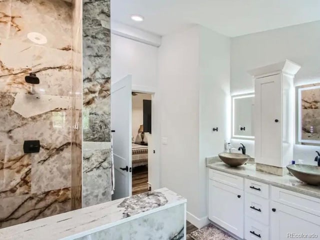 bathroom with a sink, double vanity, ensuite bathroom, and a tile shower