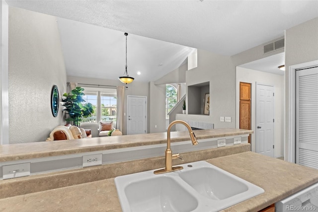 kitchen with dishwasher, lofted ceiling, sink, and pendant lighting