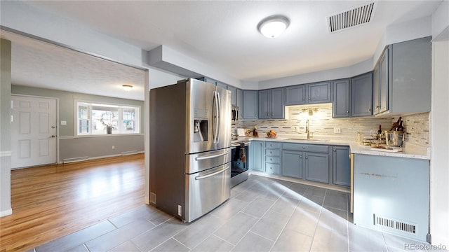 kitchen with light tile patterned floors, stainless steel appliances, tasteful backsplash, and sink