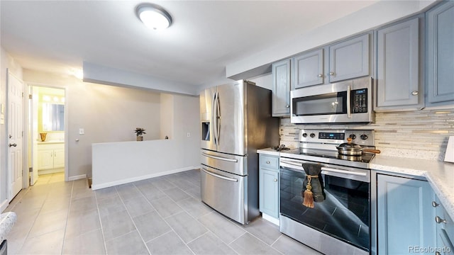 kitchen featuring backsplash, light tile patterned floors, and stainless steel appliances