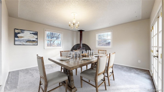 carpeted dining space featuring a textured ceiling, a tray ceiling, and an inviting chandelier