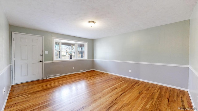 empty room with light hardwood / wood-style flooring and a baseboard heating unit