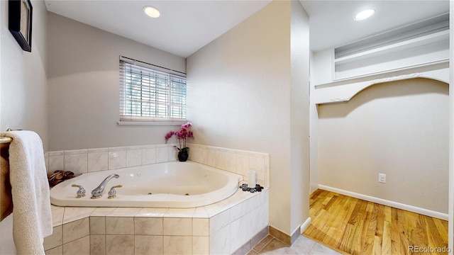 bathroom with hardwood / wood-style floors and a relaxing tiled tub