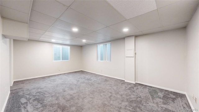 basement featuring a paneled ceiling and dark carpet