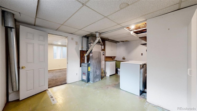 basement with heating unit, a drop ceiling, and refrigerator