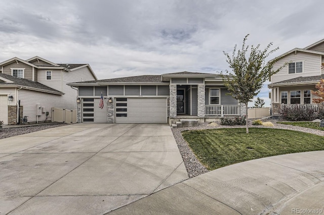 view of front of house with concrete driveway, covered porch, a front yard, a garage, and stone siding