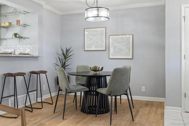 dining space featuring crown molding, baseboards, and wood finished floors