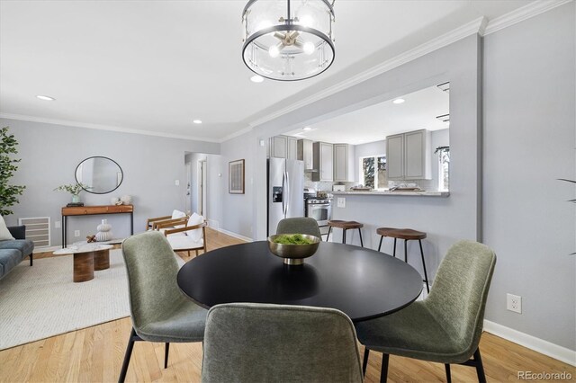 dining room with light wood-style floors, baseboards, ornamental molding, and recessed lighting