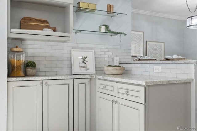 kitchen featuring open shelves, tasteful backsplash, light stone counters, and crown molding