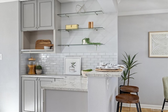 bar featuring tasteful backsplash, ornamental molding, and baseboards