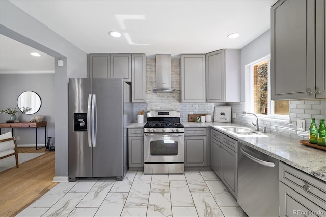 kitchen with appliances with stainless steel finishes, marble finish floor, gray cabinets, wall chimney range hood, and a sink