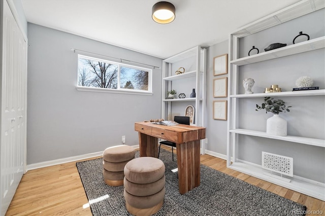 office space featuring wood finished floors, visible vents, and baseboards