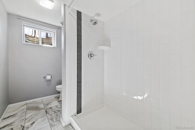 bathroom with marble finish floor, tiled shower, and toilet