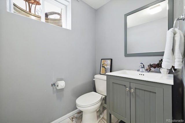 bathroom with marble finish floor, vanity, toilet, and baseboards