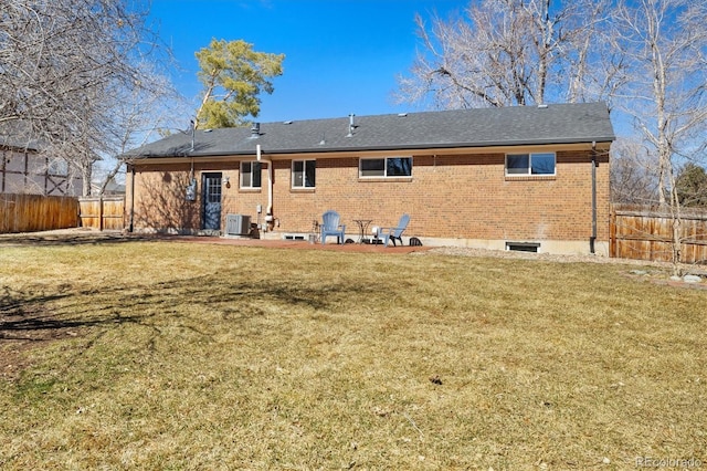 rear view of house featuring brick siding, a patio, a lawn, central AC unit, and fence