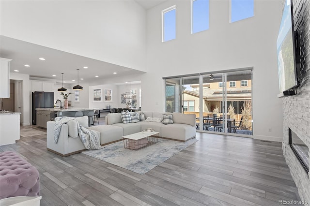 living room with a stone fireplace, plenty of natural light, and light wood-style flooring