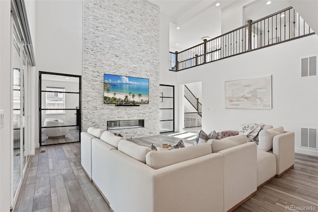 living area featuring wood-type flooring, visible vents, and a stone fireplace