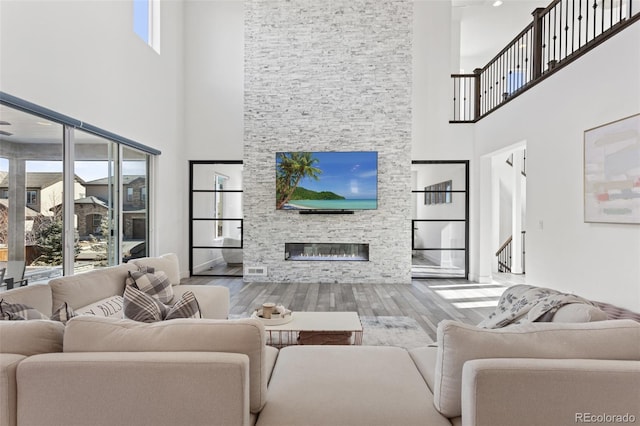 living room featuring baseboards, wood finished floors, and a stone fireplace