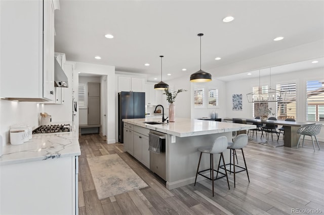 kitchen featuring light wood finished floors, appliances with stainless steel finishes, a healthy amount of sunlight, white cabinets, and a sink